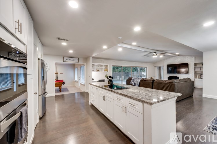 A modern kitchen with white cabinets and a marble countertop.