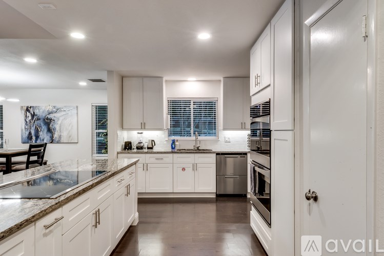 A modern kitchen with white cabinets and stainless steel appliances.