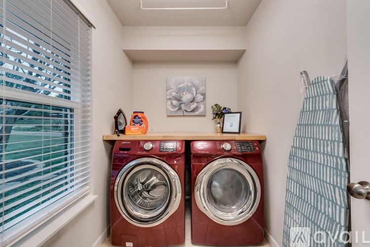 A small laundry room with a red washer and dryer.