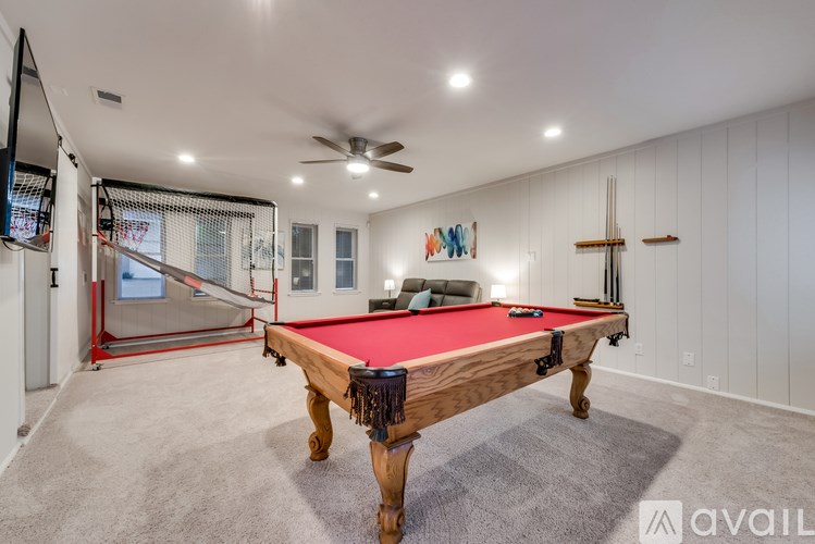 A pool table is in the middle of a room with a ceiling fan.
