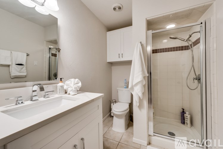 A bathroom with a white sink, toilet, and shower.