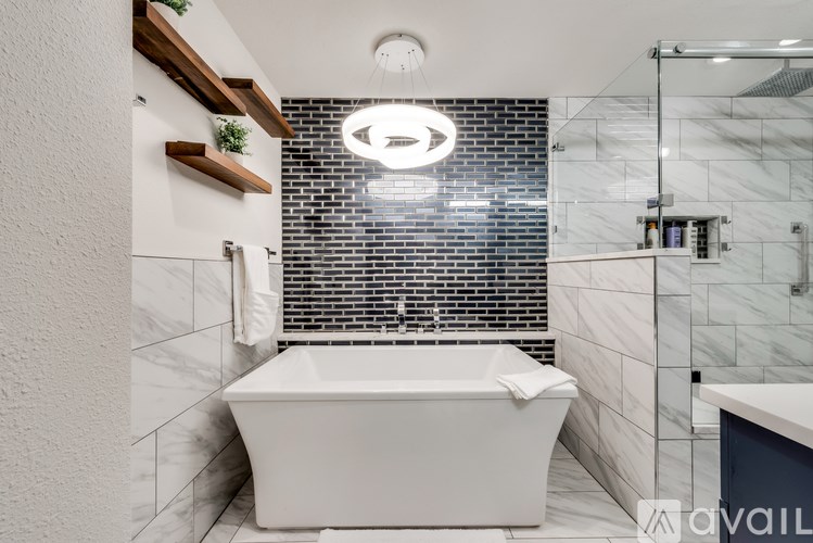 A white bathtub is in a bathroom with a black and white tiled wall.