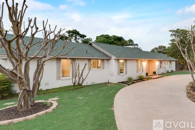 A white house with a green roof and a tree in front.