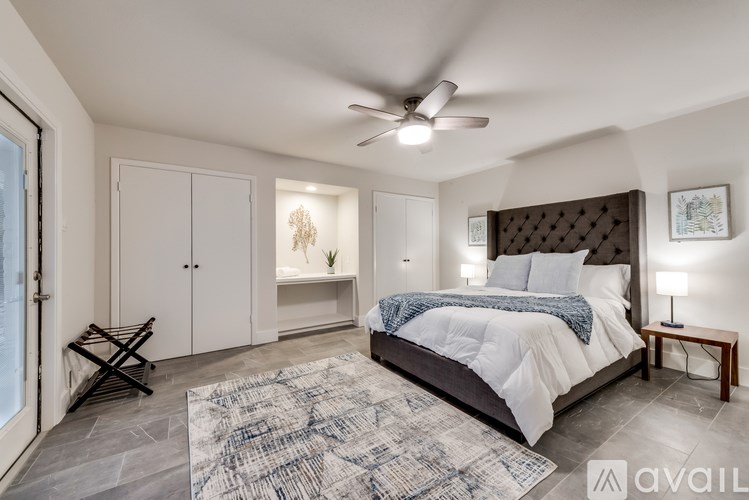 A bedroom with a large bed, a ceiling fan, and a rug on the floor.