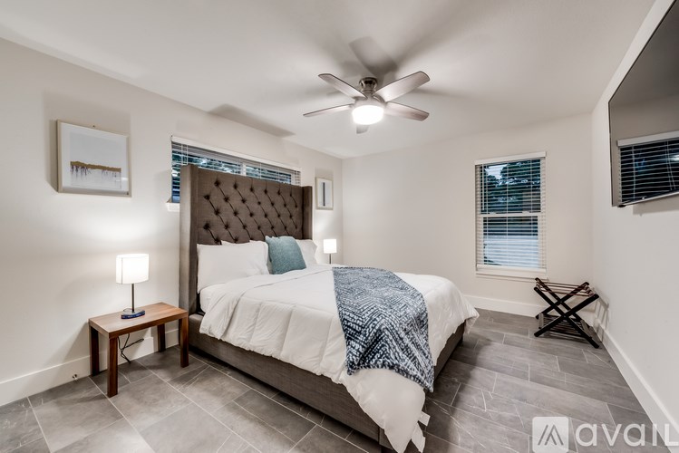 A bedroom with a bed, a ceiling fan, and a window with blinds.