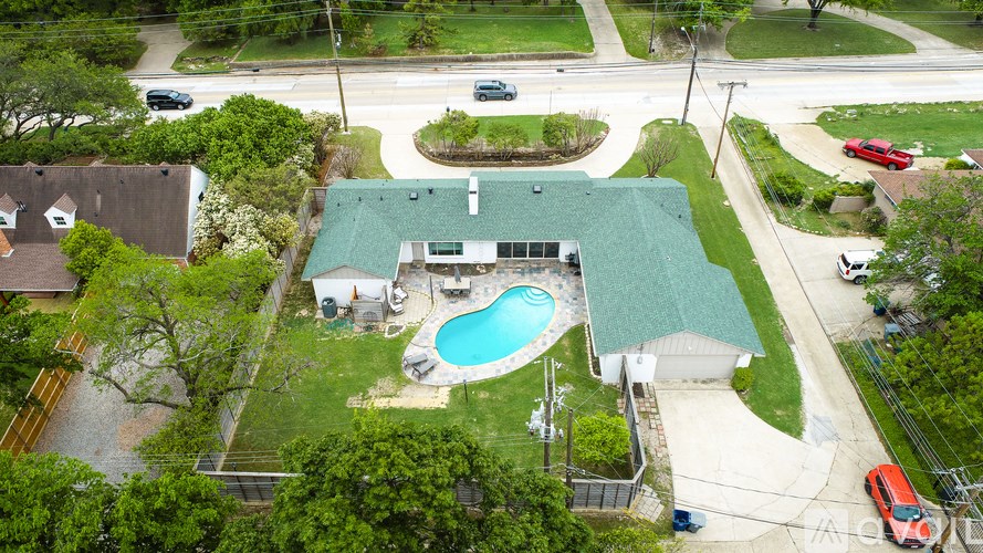 A green roofed building with a pool in front.