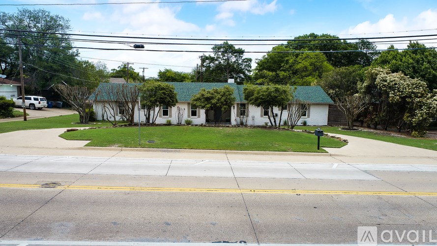 A house with a green roof is surrounded by trees and bushes.