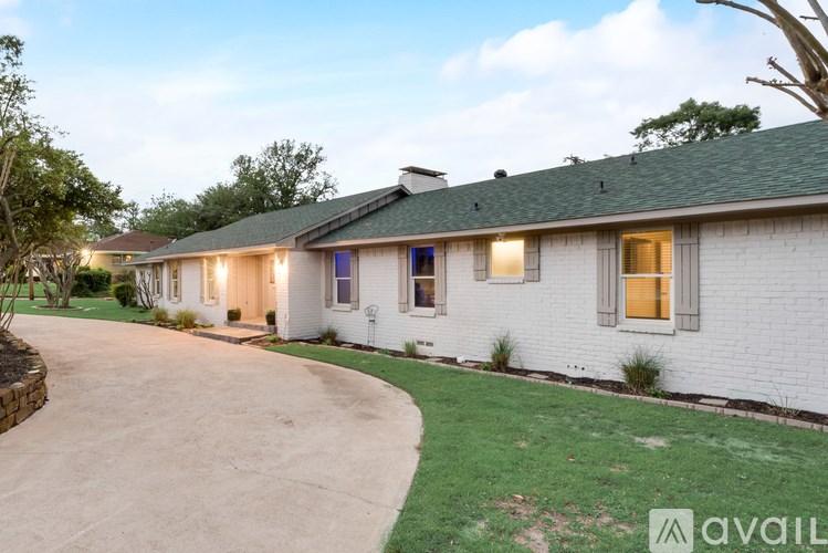 A white house with a green roof and a driveway leading to the front door.