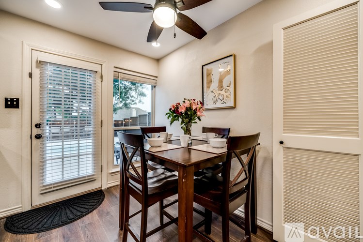 A dining room with a table set for two and a ceiling fan.