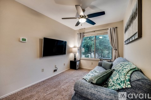 A living room with a grey couch and a flat screen TV mounted on the wall.