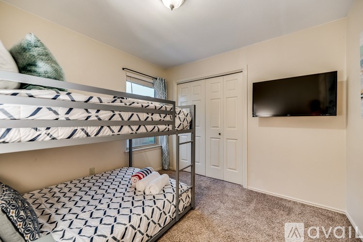 A room with bunk beds and a television mounted on the wall.