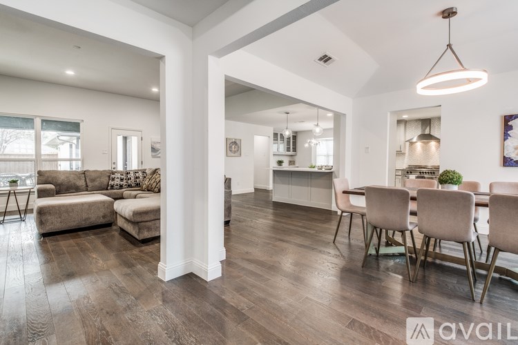 A spacious living room with a dining area in the background.