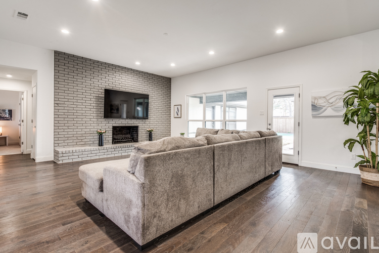 A modern living room with a grey sofa and a brick wall.