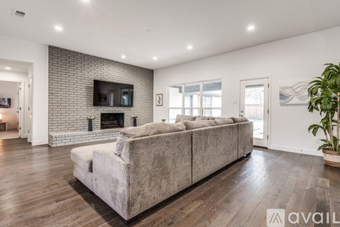 A modern living room with a grey sofa and a brick wall.
