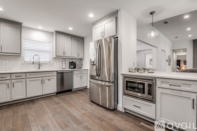A modern kitchen with a stainless steel refrigerator and wooden flooring.