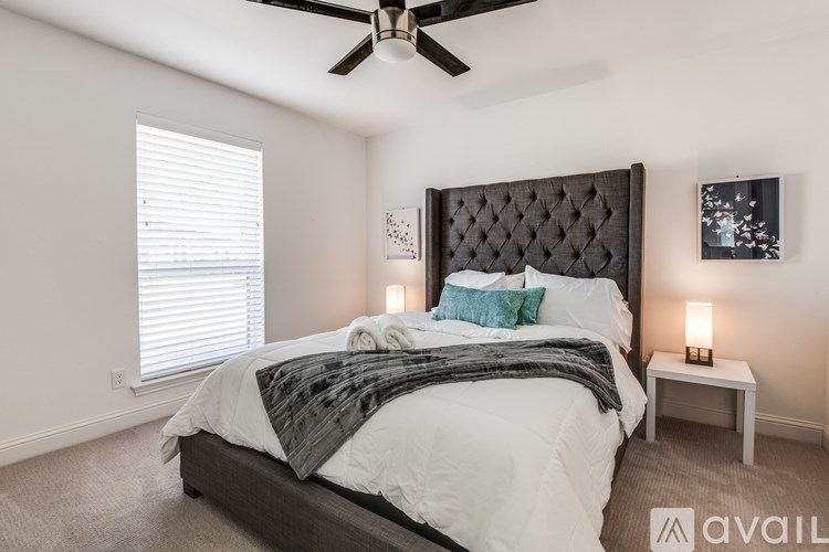 A bedroom with a large bed and a ceiling fan.