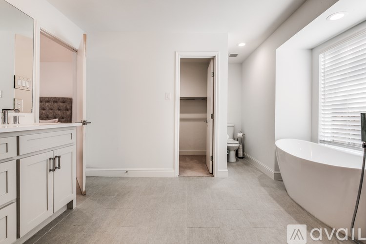 A bathroom with a tub, sink, and toilet is available for rent.