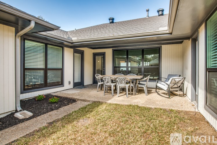 A patio with a table and chairs is in front of a house.
