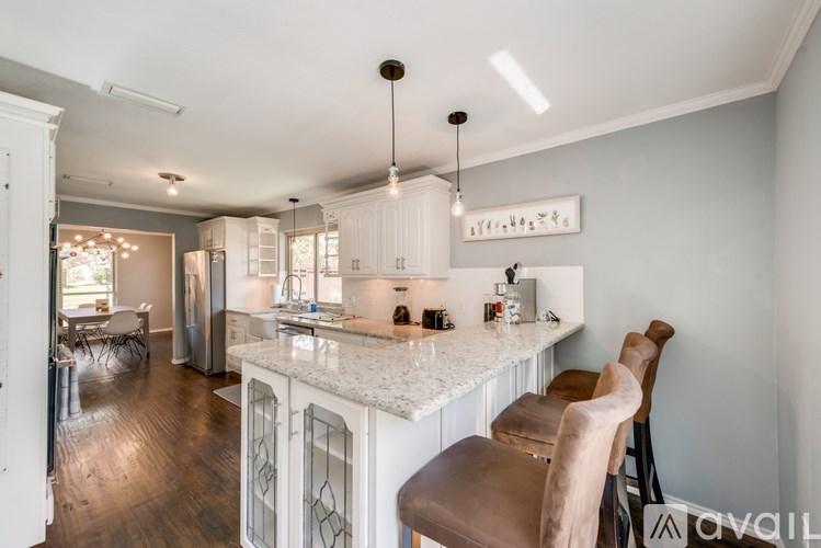A kitchen with a white countertop and brown chairs.