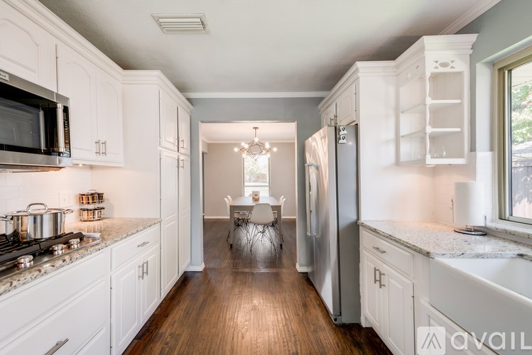 A kitchen with white cabinets and a wooden floor.