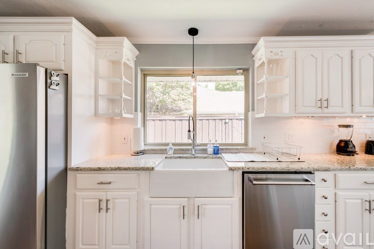A kitchen with white cabinets and a marble countertop.
