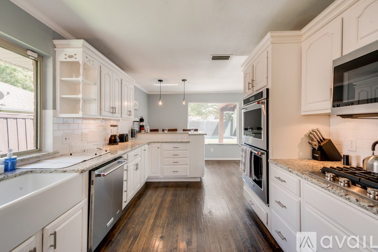 A kitchen with white cabinets and appliances, a large island, and a view of the backyard.