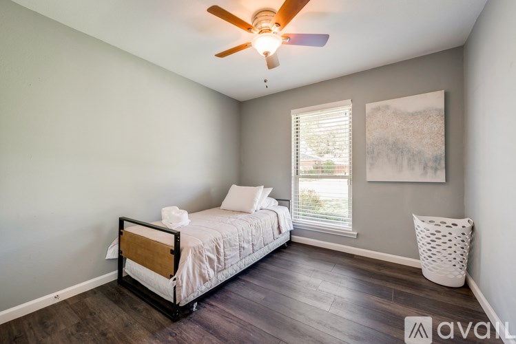 A bedroom with a bed, a ceiling fan, and a window with blinds.