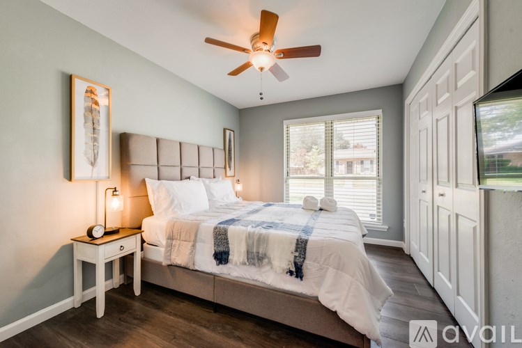 A bedroom with a bed, a nightstand, and a ceiling fan.