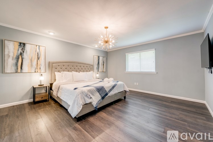 A bedroom with a large bed and a television mounted on the wall.