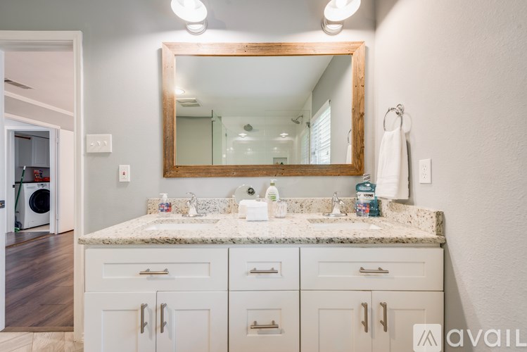 A bathroom with a marble countertop and white cabinets.