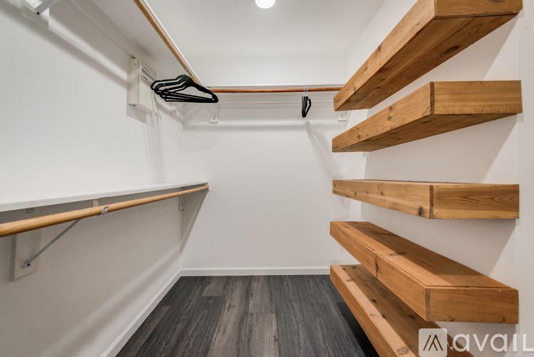 A white wall with a coat hanger and a wooden shelf.
