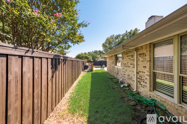A house with a wooden fence and green grass in front.