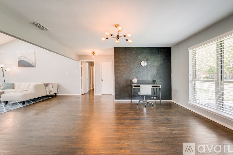 A spacious living room with a white sofa and a wooden floor.