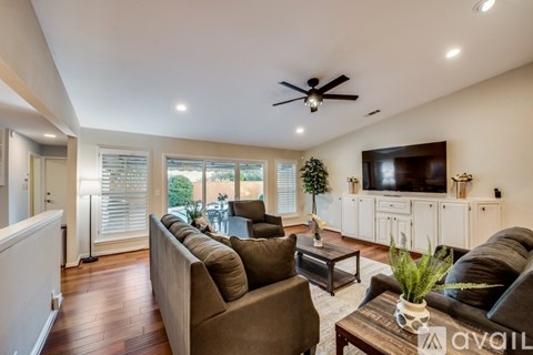 A living room with a brown couch and a ceiling fan.