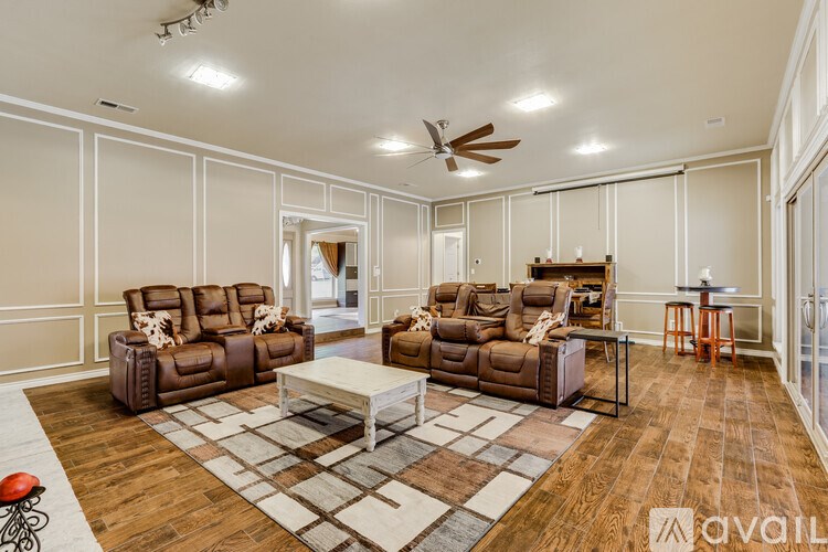 A living room with brown leather furniture and a ceiling fan.