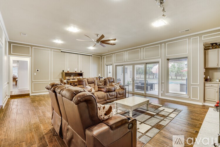 A spacious living room with brown leather couches and a ceiling fan.