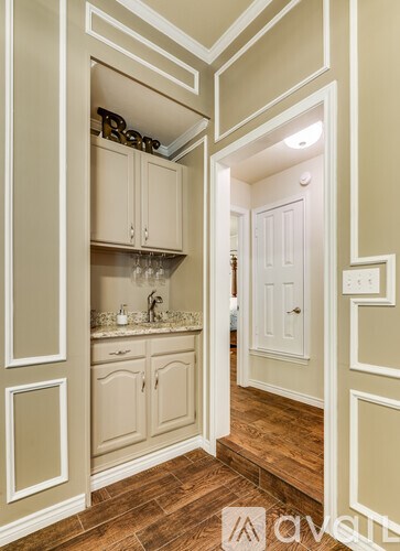 A kitchen with white cabinets and a wooden floor.