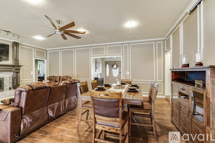 A living room with a brown leather couch and a dining table with chairs.