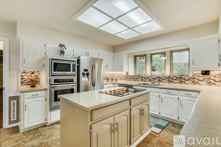 A kitchen with a large island in the middle and a skylight above it.