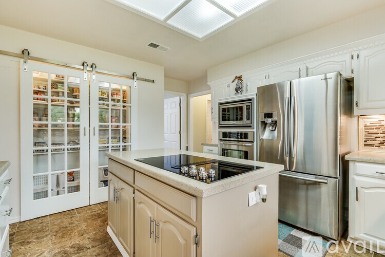 A kitchen with a skylight and stainless steel appliances.