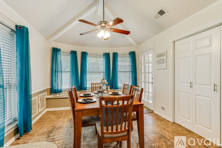 A dining room with a table set for four and a ceiling fan.
