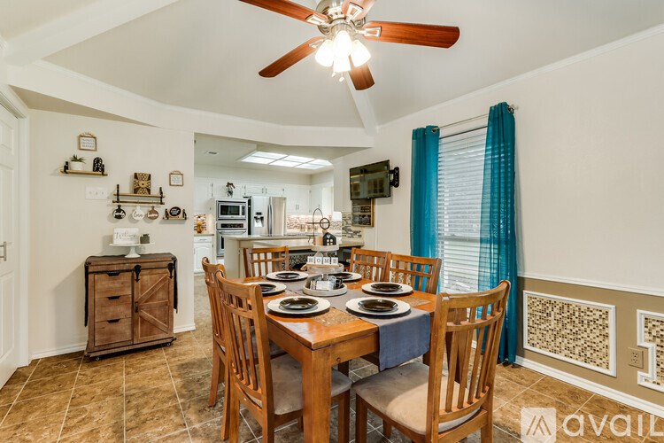 A dining room with a table set for four and a fan above it.