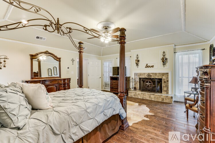A bedroom with a large bed and a fireplace.