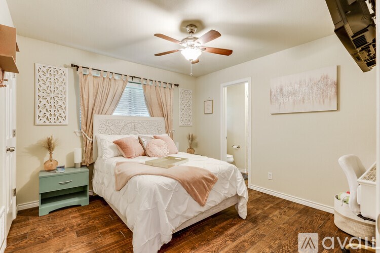 A bedroom with a white bed and a ceiling fan.