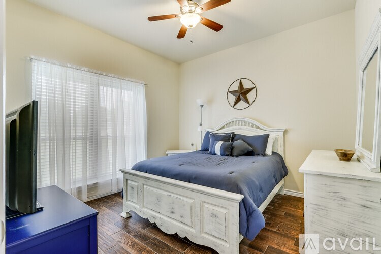 A bedroom with a bed, dresser, and ceiling fan.