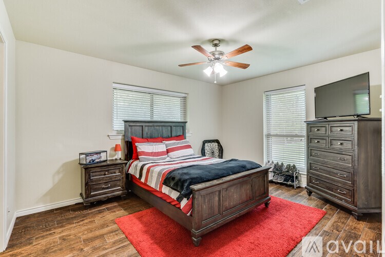 A bedroom with a bed, dresser, and ceiling fan.