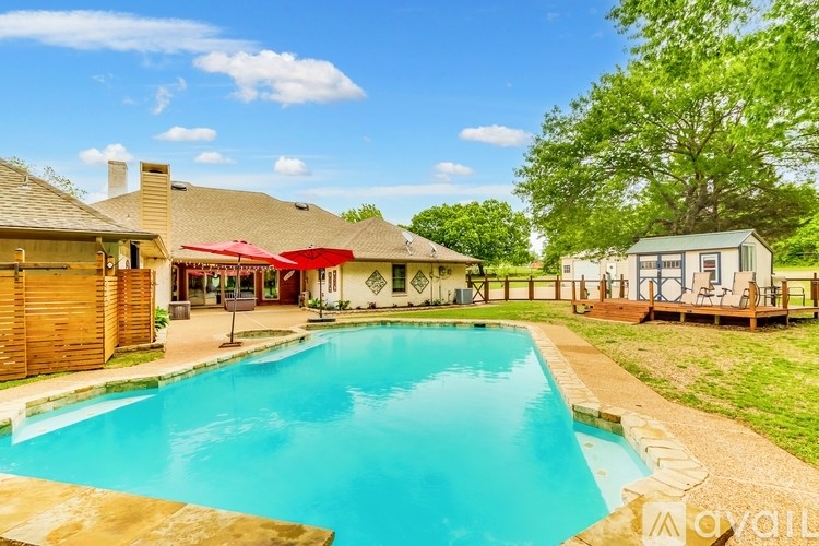 A pool in a backyard with a house and a tree.