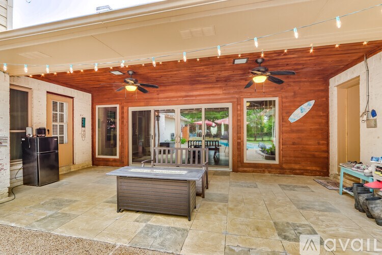 A patio with a ceiling fan and lights, a refrigerator, and a table.