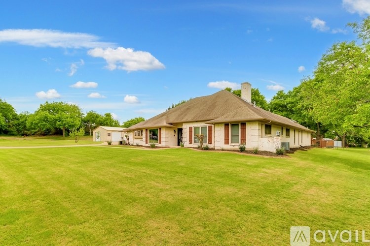 A house with a brown roof and a large lawn in front.