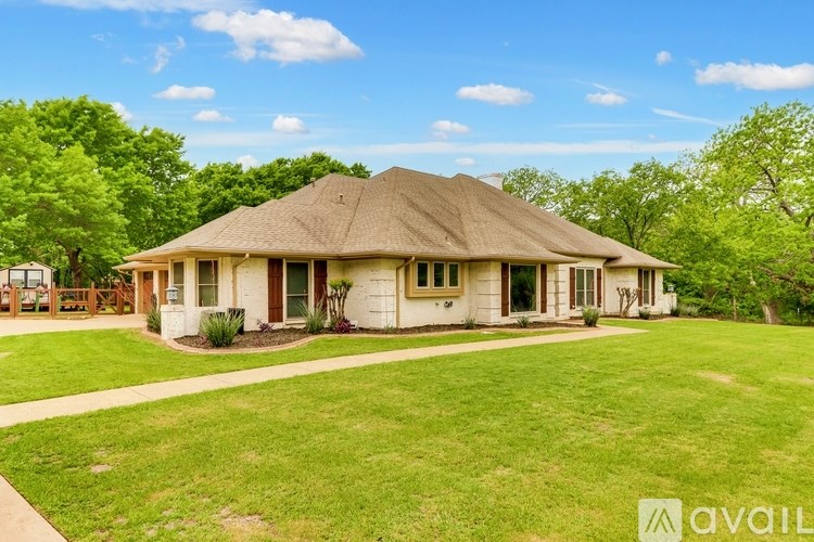 A house with a thatched roof is surrounded by a well-kept lawn.